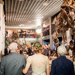 A woman getting walked down the isle during her wedding in Dinosaur Hall.